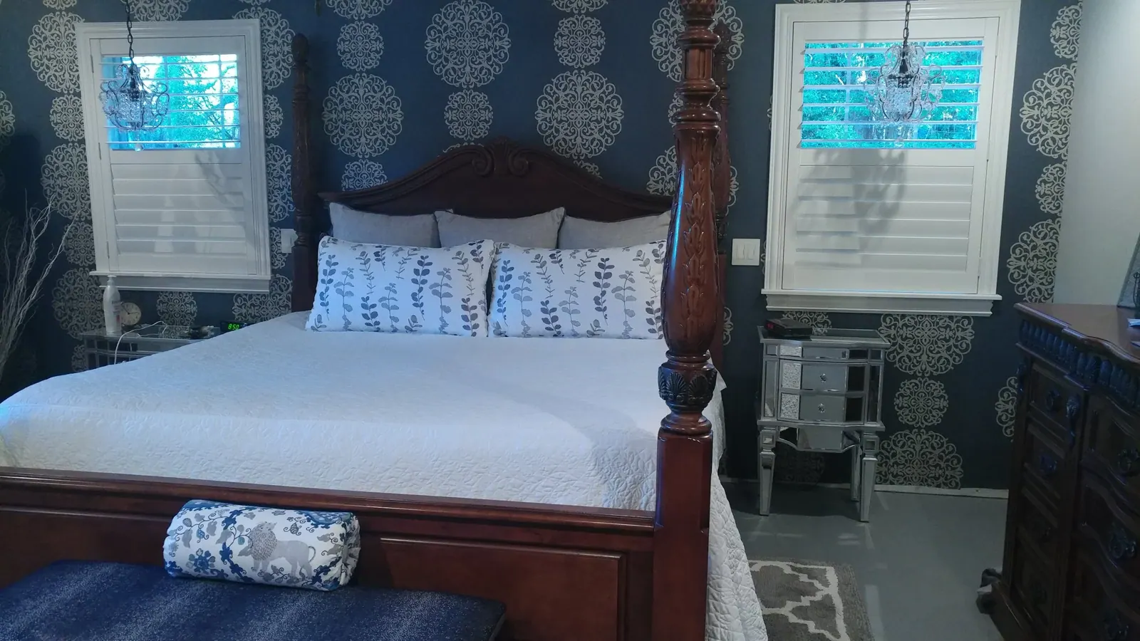 Custom Bedroom Bedding, Quilted coverlet, vine-print shams, and a lion-motif bolster on a four-poster bed, with white shutters on either side. By Custom Fabric Creations, St. Petersburg, FL.