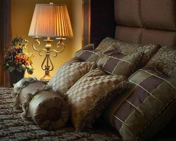 Custom Pillows & Bolster, Layered decorative pillows and a fringed bolster on a channel-tufted headboard, sewn in mixed designer fabrics. By Custom Fabric Creations, St. Petersburg, FL.