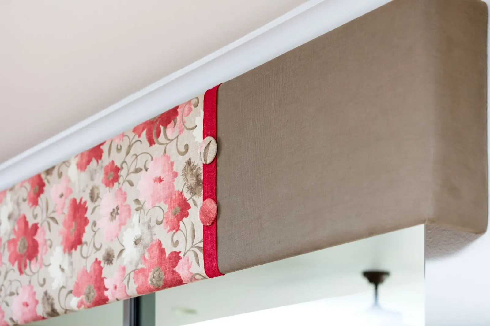 Floral Upholstered Cornice, A two-tone box cornice with floral face fabric, solid return, red contrast trim, and covered buttons. By Custom Fabric Creations, St. Petersburg, FL.